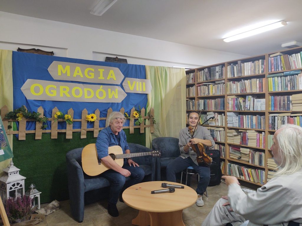 Muzycy ze skrzypcami i gitarą na tle dekoracji