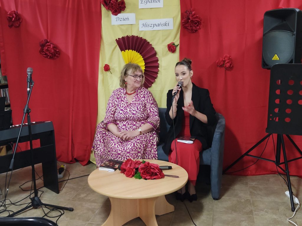 Dwie panie na scenie, z przodu stolik z różami