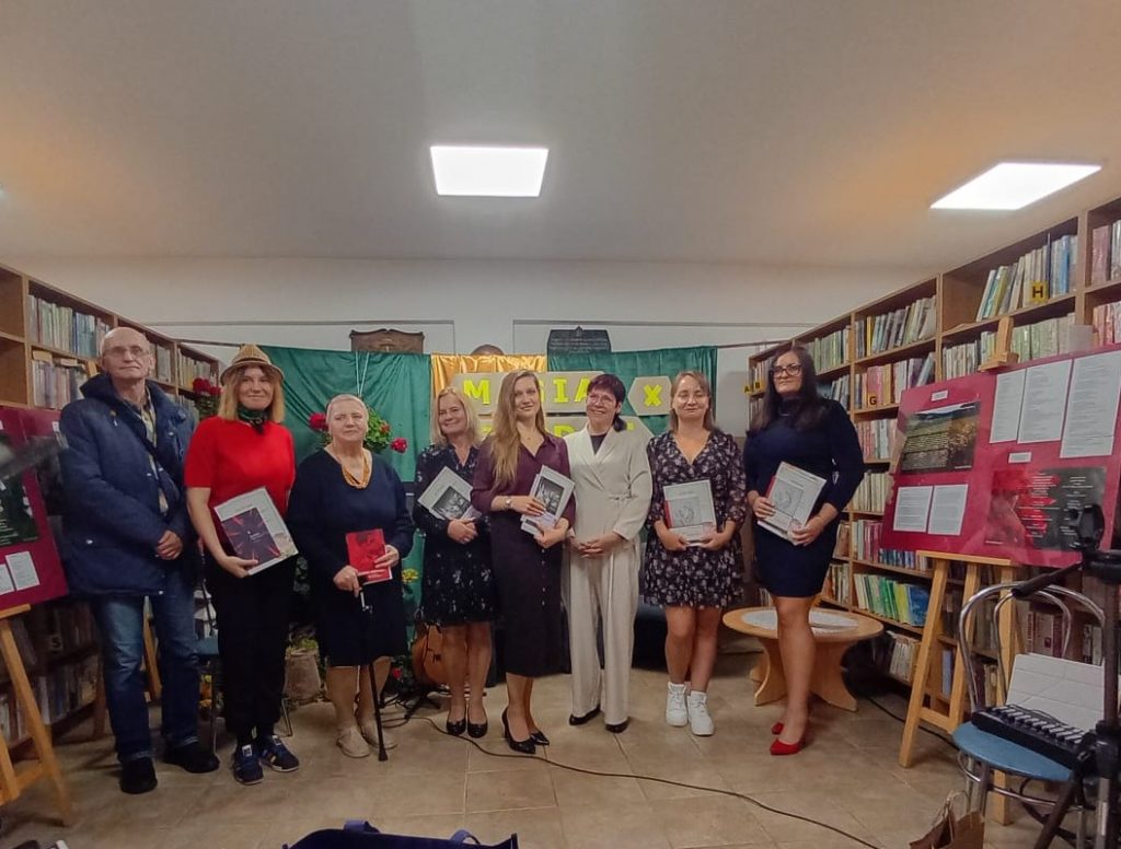 Nagrodzeni i szefowa biblioteki na tle dekoracji